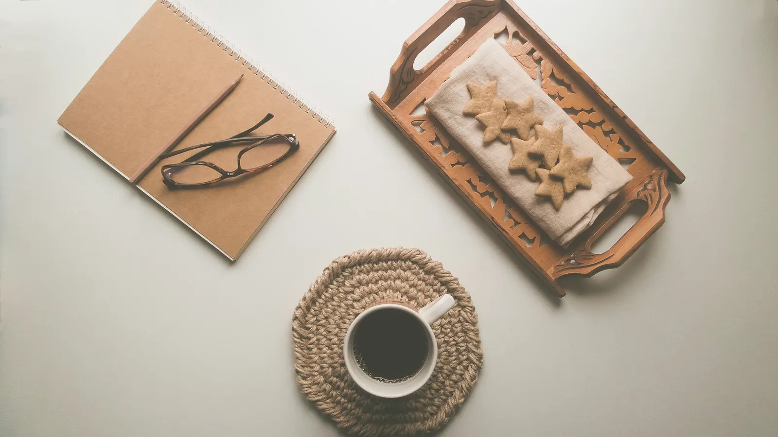A notebook, glasses and a warm drink on a woven coaster, ready for a consultation