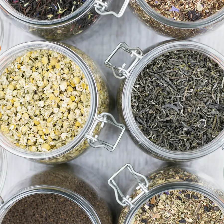 Open glass jars of loose leaf tea, including chamomile and herbal blends